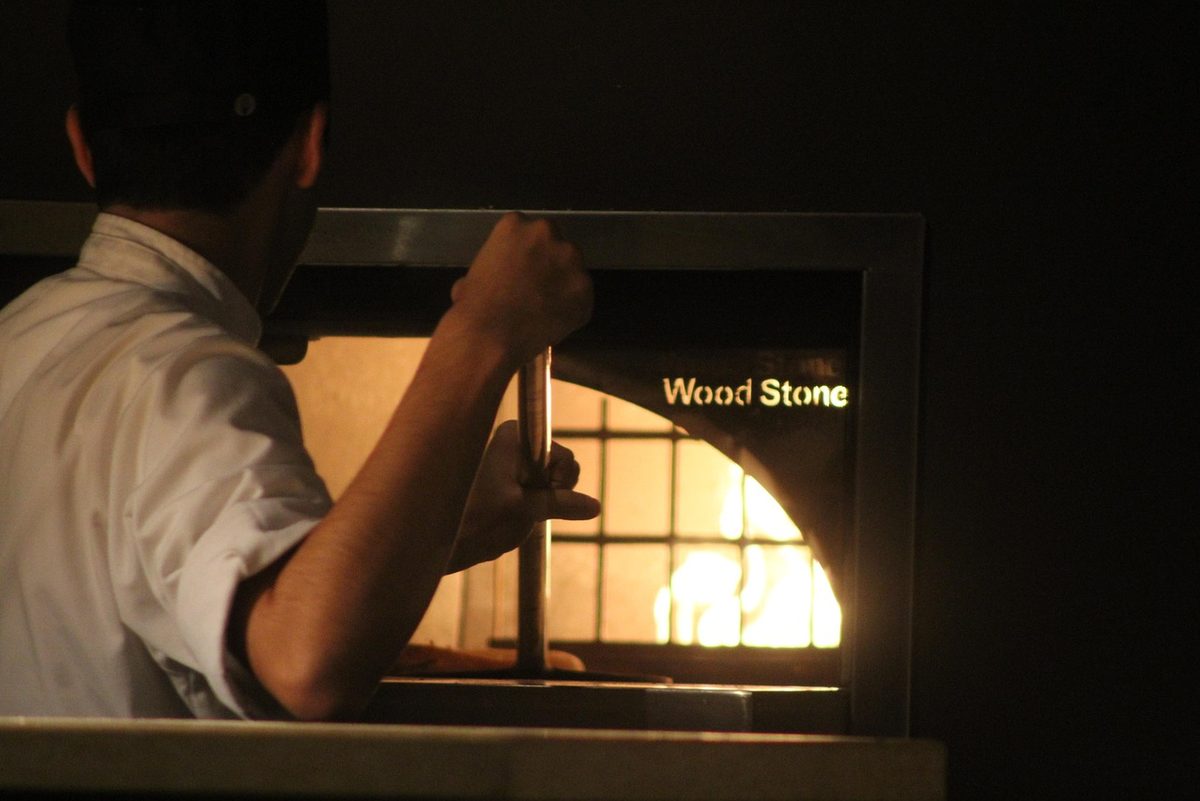 Professional wood-fired pizza restaurant kitchen with expert chefs
